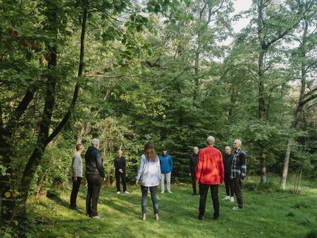 Grupa osób idąca powoli gęsiego leśną ścieżką